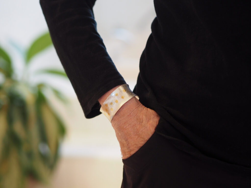 wide silver and gold confetti cuff on wrist