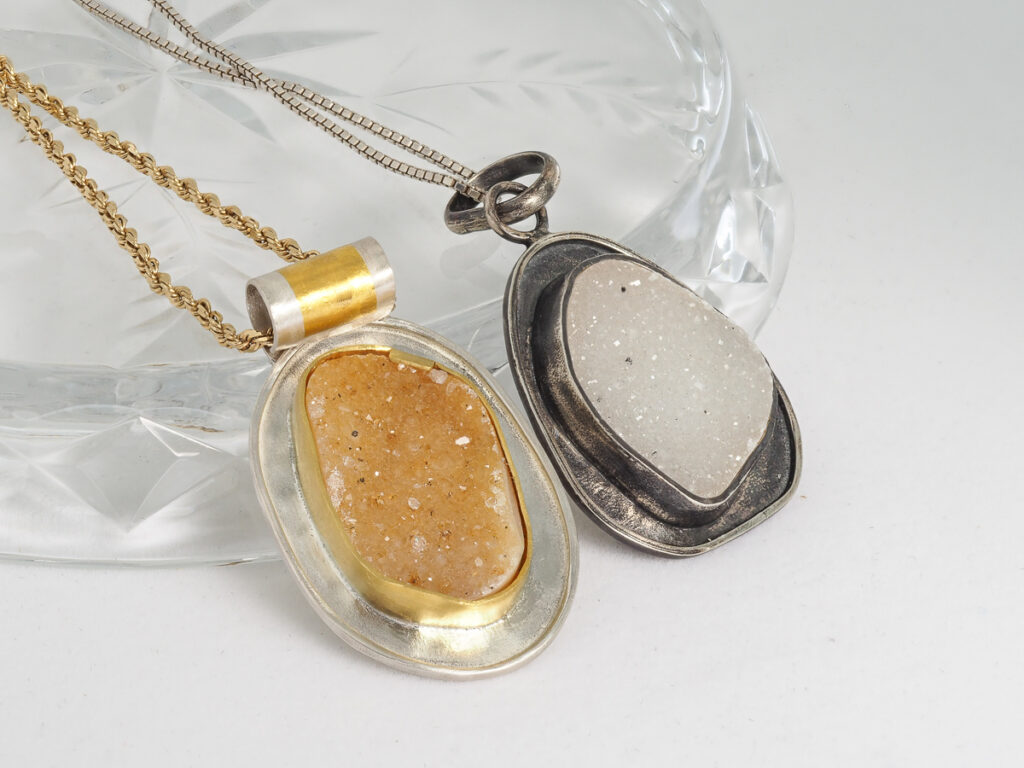 Two druzy natural gemstone pendants, one in gold and one in white druzy set in silver.