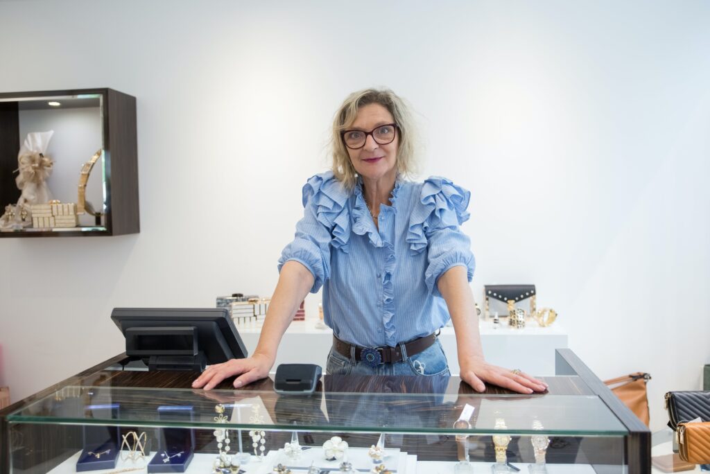 A jewelry designer at a display counter, sharing the story of heirloom quality and the endurance of noble metals.
