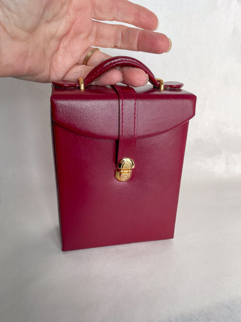 red travel jewelry case with hand