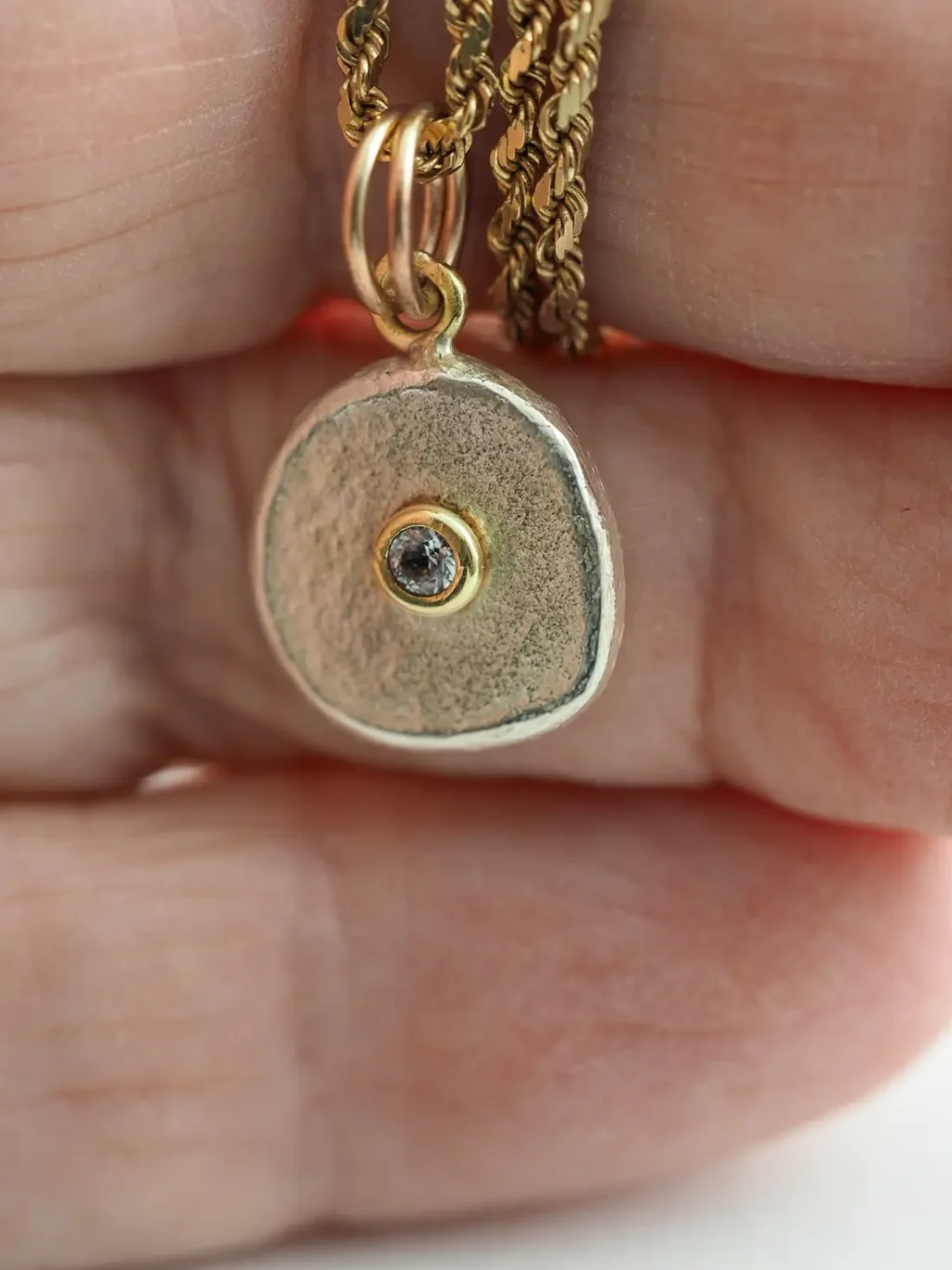 a gold and diamond charm held in a hand