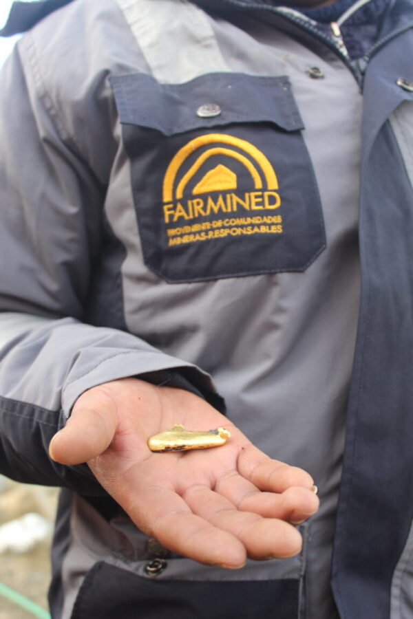 Fairmined uniformed man with a large gold nugget in palm of hand