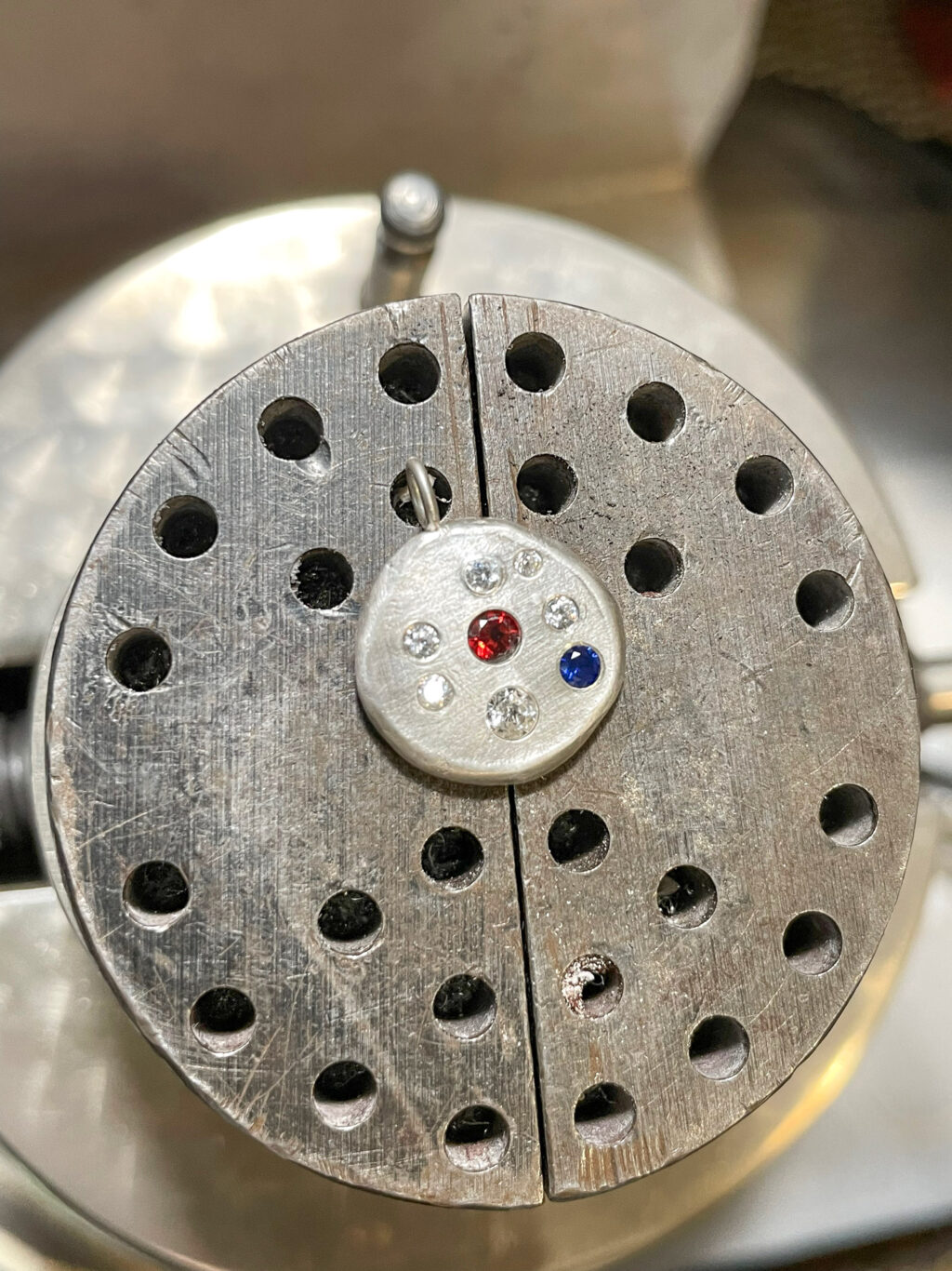 A Charm pendant in the stone setting vise